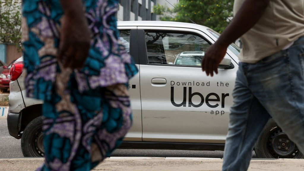 People walk past an Uber car in Lagos.